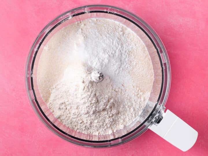 Flour, sugar, baking powder and salt added to the bowl of a food processor.