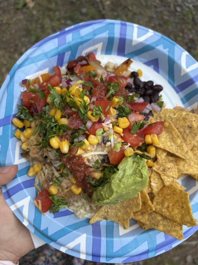 Tomatoes, corn, minced onions, black beans, salsa, cheese, guacamole, and rice piled on Mexican shredded chicken for taco bowls