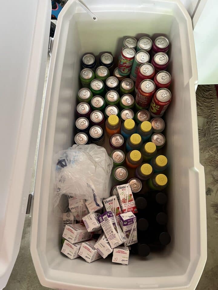 cans, bottles, and juice boxes packed in drink cooler with loose ice on top
