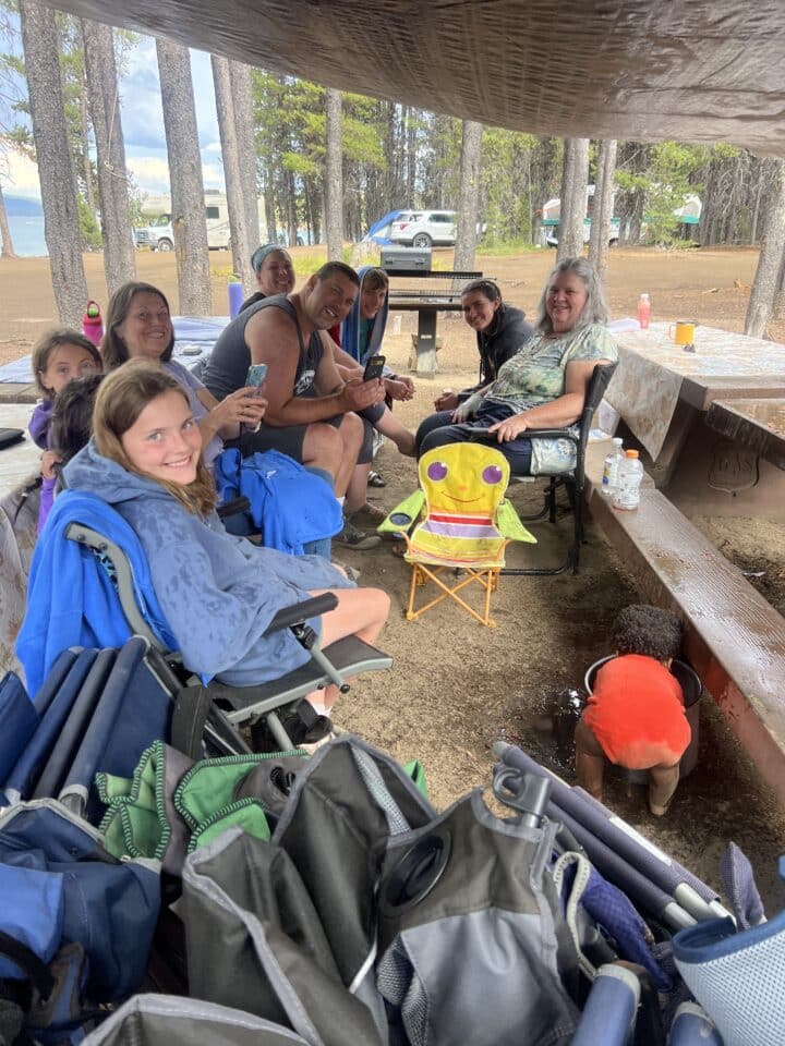 a family hanging out under a canopy to stay dry while it's raining at camp