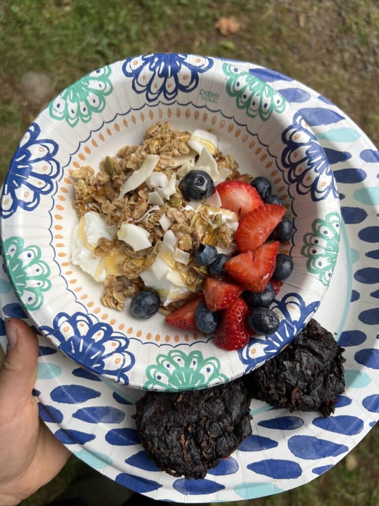 paper bowl of homemade granola, fresh fruit, and double chocolate zucchini muffins