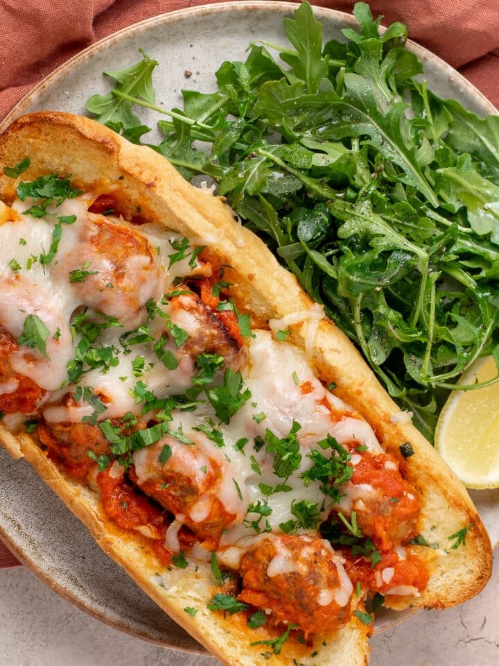 Garlic bread sub with meal prep meatballs, marinara, melted cheese and a side of arugula.
