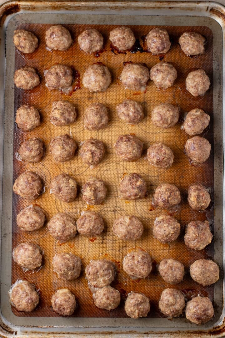 Baked meal prep meatballs arranged on a lined sheet pan.