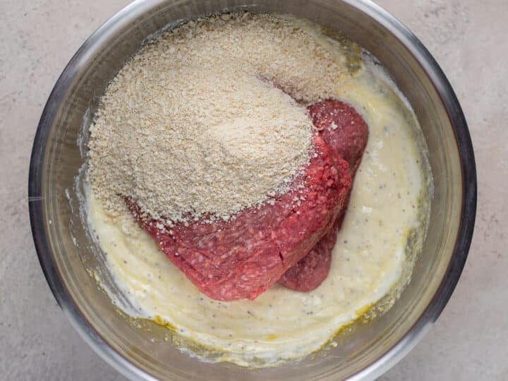 Ground beef and panko breadcrumbs added to the seasoned ricotta mixture in a bowl.
