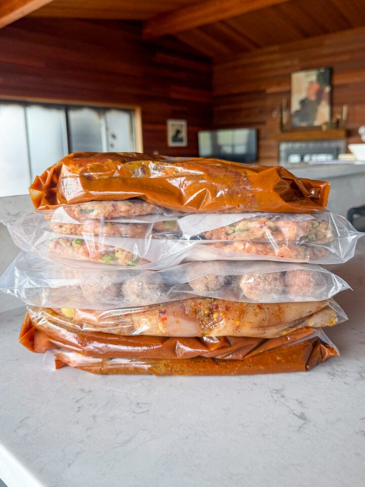 Stack of freezer meal prep bags filled with make-ahead dinners, chicken burgers and meatballs