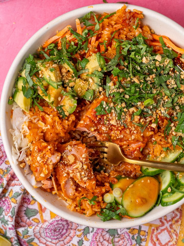 Close-up of crispy rice and salmon with peanut sauce, avocado, cucumber, herbs and crushed peanuts