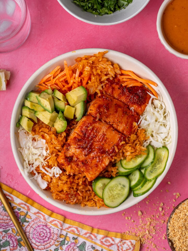 Crispy rice bowl with salmon, shredded cabbage, shredded carrots, sliced cucumber and diced avocado