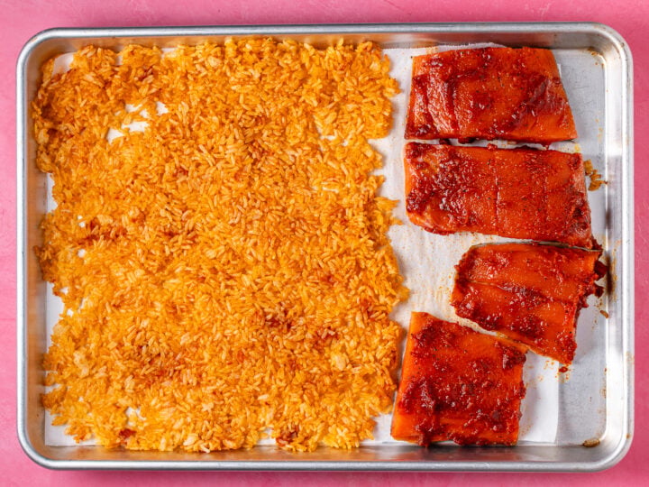 Salmon fillets added to the baking sheet alongside red curry rice