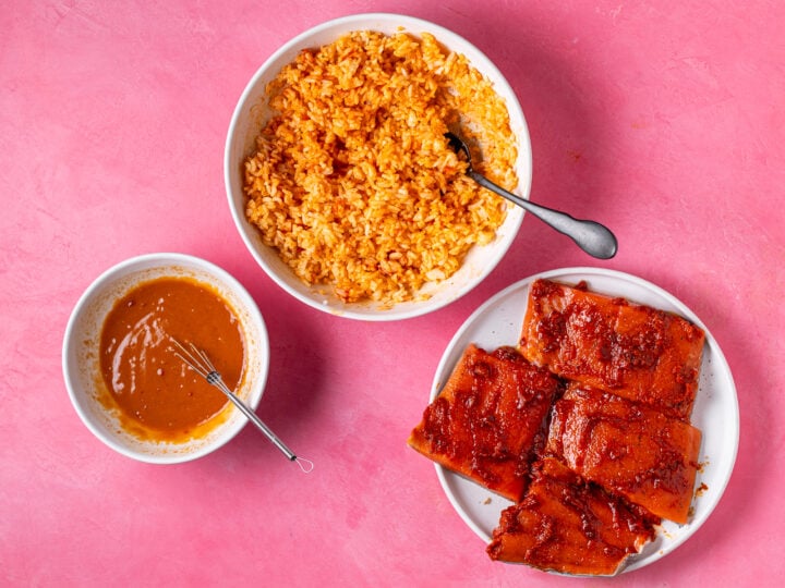Red curry jasmine rice, sweet chili peanut sauce and salmon fillets prepared for baking each in separate dishes
