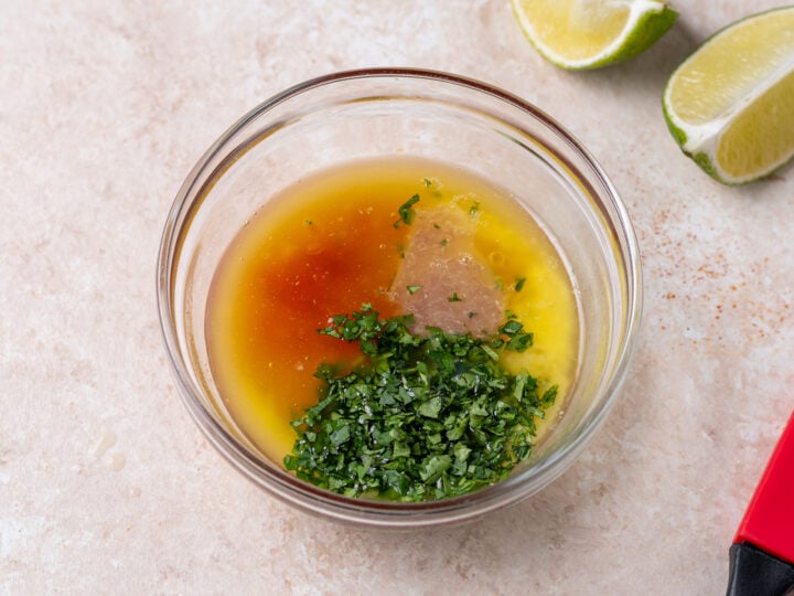 Melted butter, sweet chili sauce, lime juice and chopped cilantro in a small glass bowl.