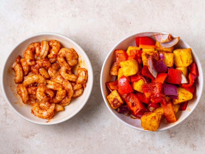 Seasoned shrimp alongside seasoned fresh pineapple chunks, red bell pepper and red onion.