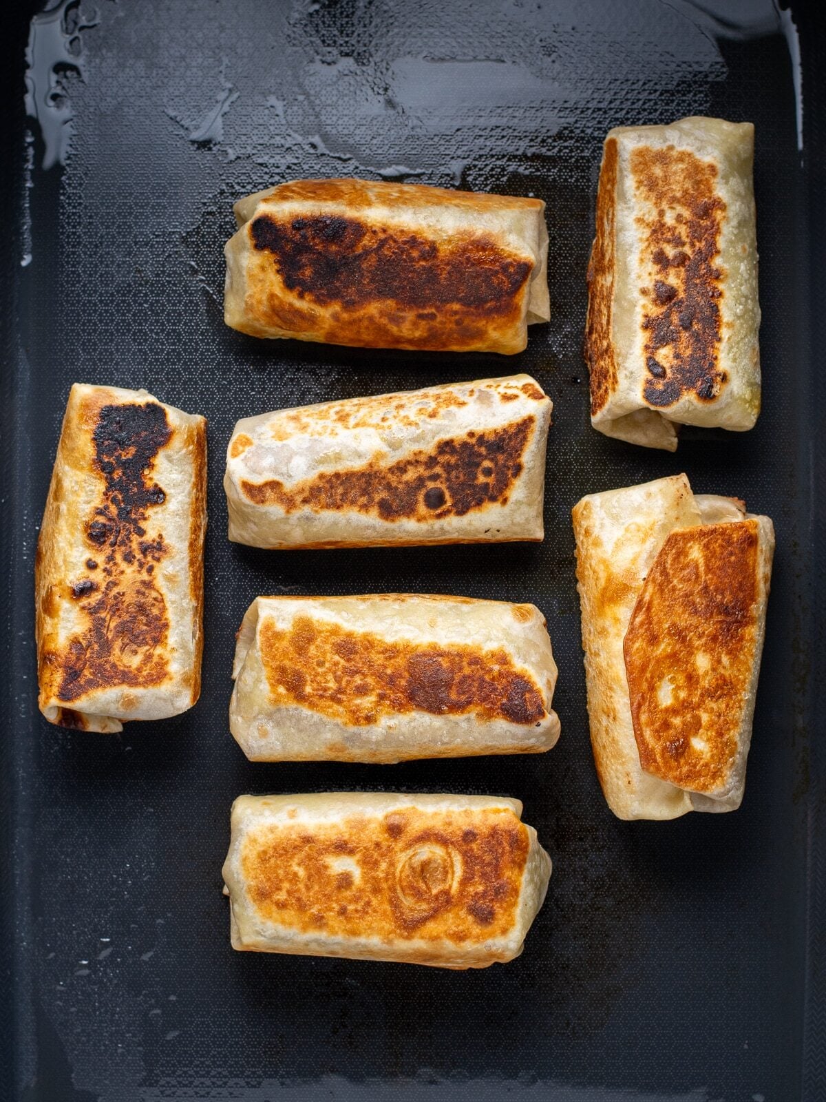 toasted bean and cheese burritos on a black griddle