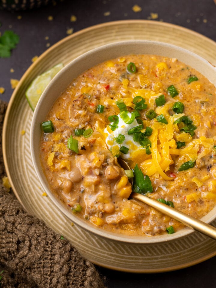 Thick and creamy white bean chicken chili with Italian sausage, corn and white beans topped with cheese, Greek yogurt and green onions.
