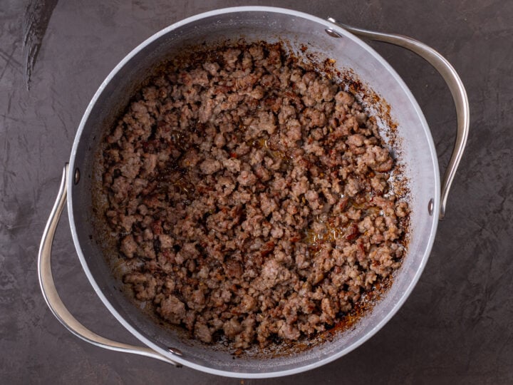 Italian sausage browned and crumbled in a large pot.
