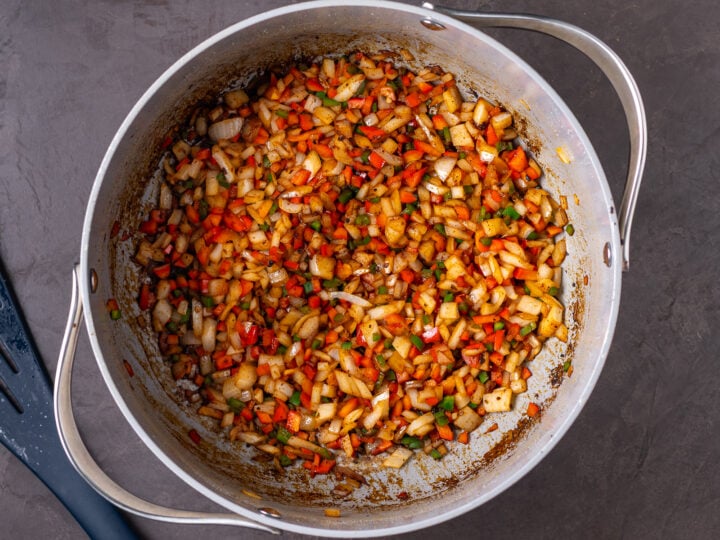 Diced onion, red bell pepper and jalapeño sautéed with spices and browned bits in a large pot.
