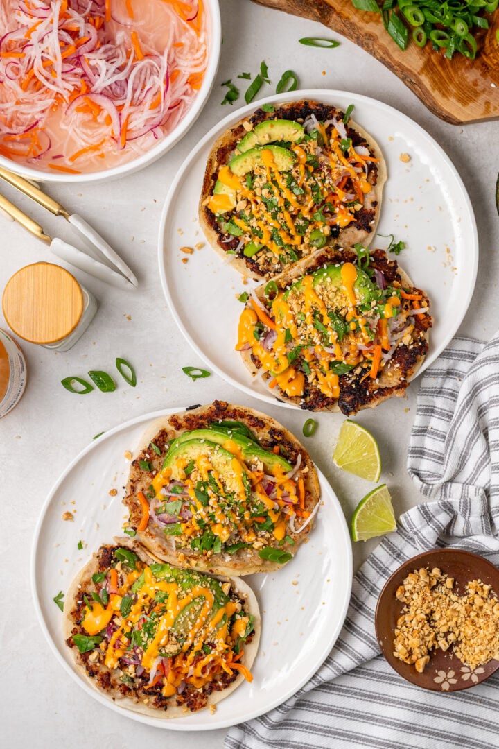 Four banh mi smash tacos topped with pickled vegetables, avocado, crushed peanuts, cilantro and sriracha mayo.