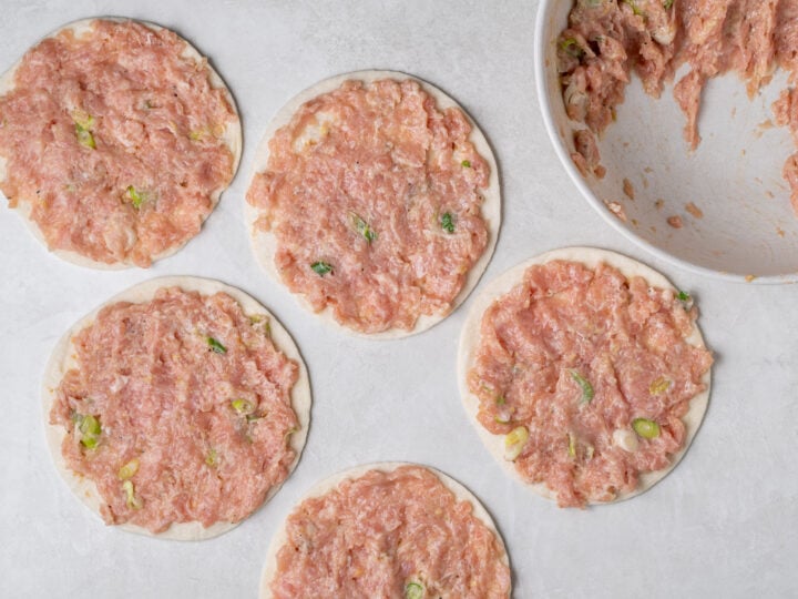 Uncooked ground chicken mixture spread evenly to the edges of five street taco-sized flour tortillas.