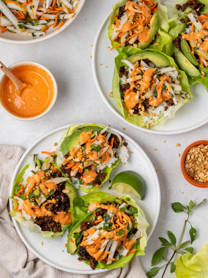 Gochujang ground beef lettuce wraps topped with rice, pickled pear slaw, avocado, crushed peanuts and creamy gochujang aioli