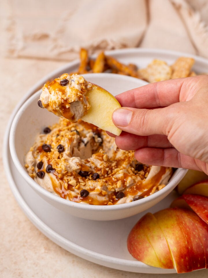 Apple slice being dipped into peanut butter Greek yogurt dip