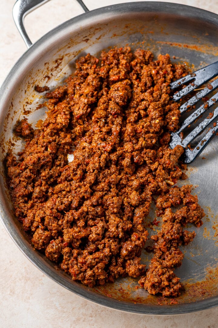 Saucy ground beef taco meat with homemade taco seasoning in a skillet with a black spatula.