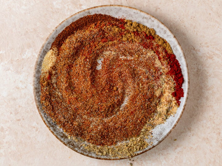 Mexican spices mixed together on a ceramic plate for homemade taco seasoning.